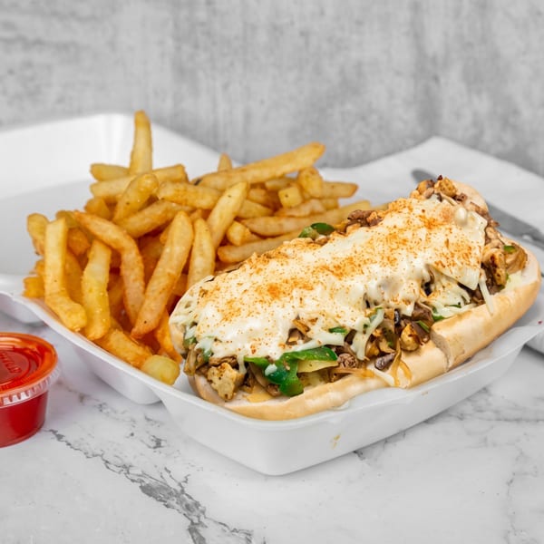 Cheesesteak sandwich with fries and two dipping sauces in a white takeout container.