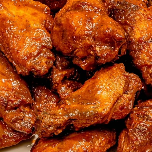 Close-up of a pile of glistening, saucy chicken wings, ready to be served.