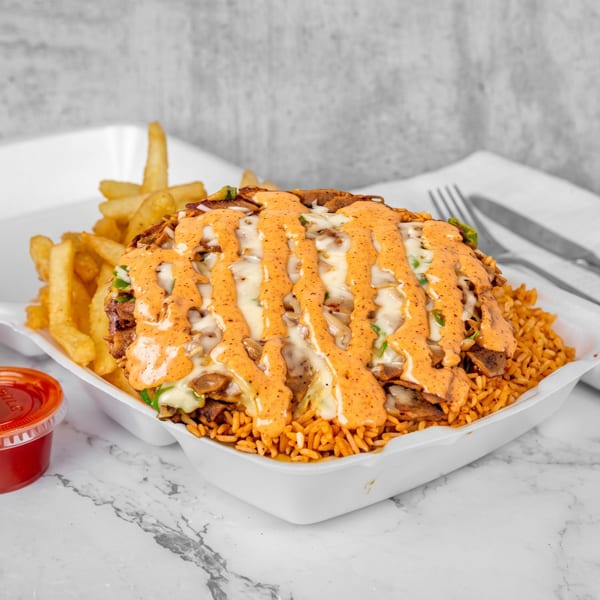 A takeout container filled with rice, meat, melted cheese, and orange sauce, with fries and two sauce cups.