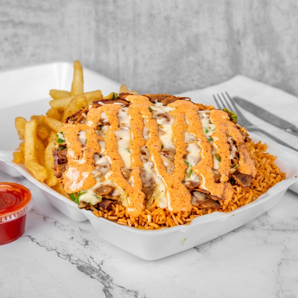 A takeout container filled with rice, meat, melted cheese, and orange sauce, with fries and two sauce cups.